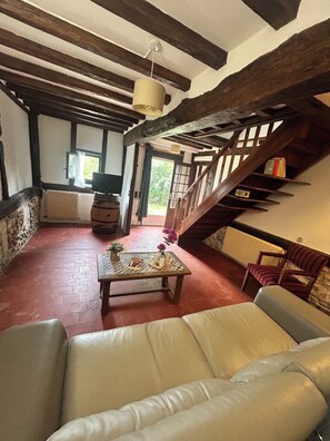 Ein rustikales Interieur mit einer Holztreppe, einem Ledersofa, einem Tisch mit Dekoration und einem Fernseher.
