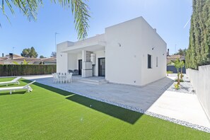 Una casa moderna con patio, mobiliario exterior y piscina.