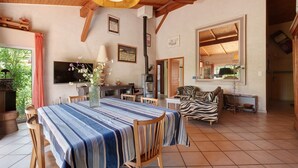 Amplia sala de estar con mesa de comedor, sillas, sofá, televisor y chimenea.