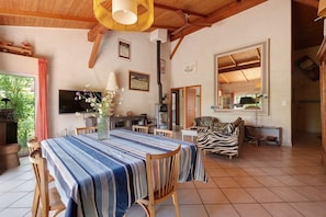 A spacious living area with a dining table, chairs, a sofa, a TV, and a fireplace.