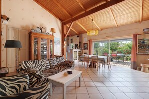Een ruime woonkamer met een sofa met zebraprint, een eettafel en een keuken die zichtbaar is door een geopende deur.