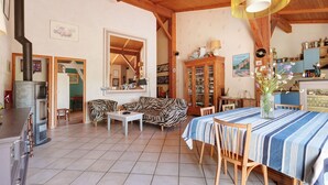 Amplia sala de estar con chimenea, una mesa de comedor con sillas, un sofá y una zona de cocina con armarios y estufa.