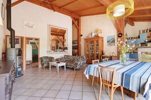 Un vaste espace de vie doté d’une cheminée, d’une table à manger avec des chaises, d’un canapé et d’un coin cuisine avec des placards et une cuisinière.