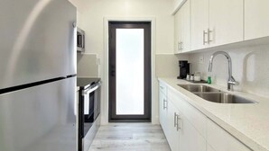 Una cocina moderna con un refrigerador de acero inoxidable, un microondas, una cafetera y un lavamanos.