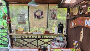 A wooden deck with a table set for dining, surrounded by greenery. - Supia Pension (Pyeongchang)
