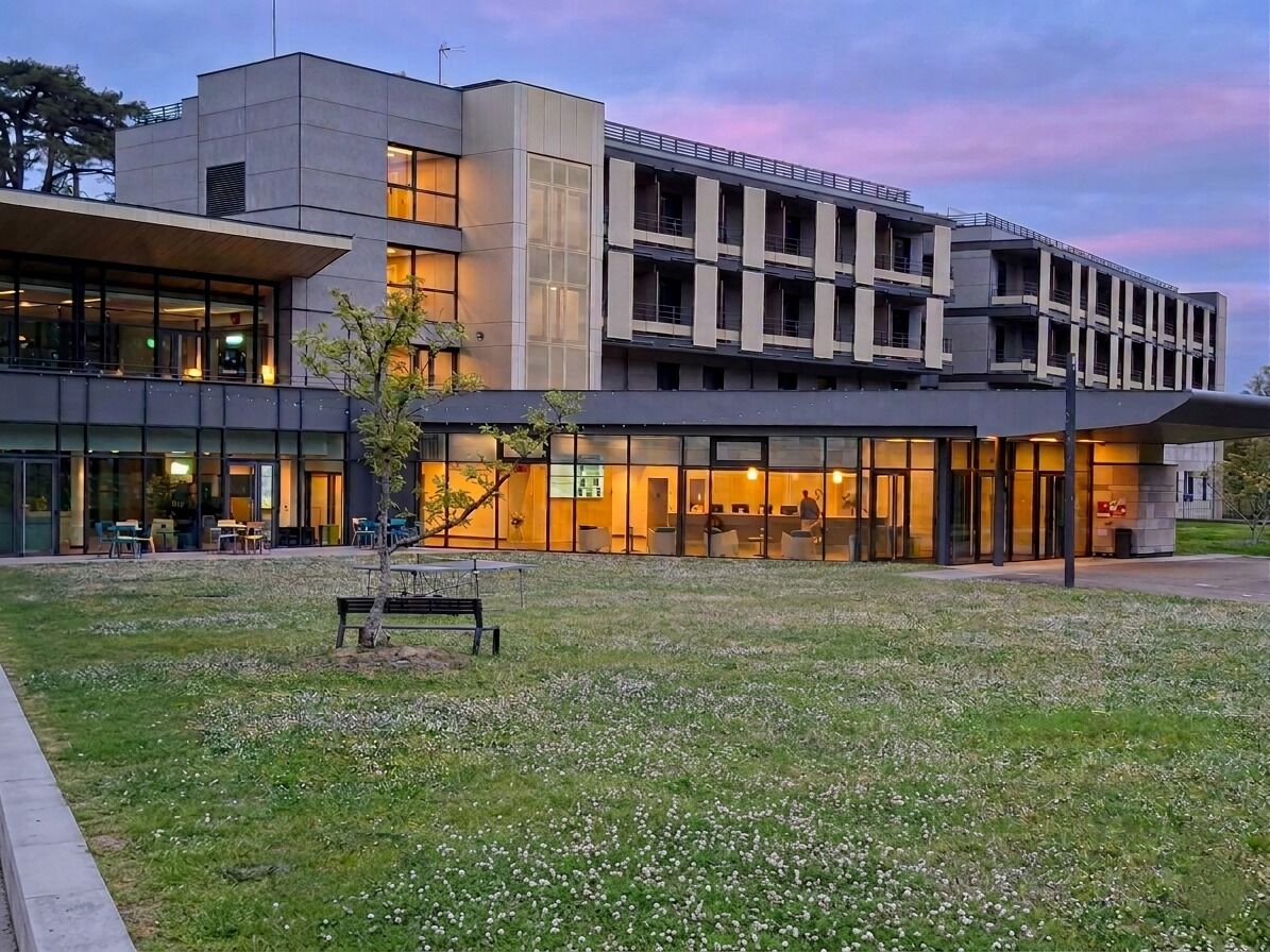 A modern building with a flat roof, large windows, and a grassy courtyard.