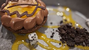 Un dessert au chocolat, agrémenté d’éléments de couleur jaune, présenté dans une assiette.