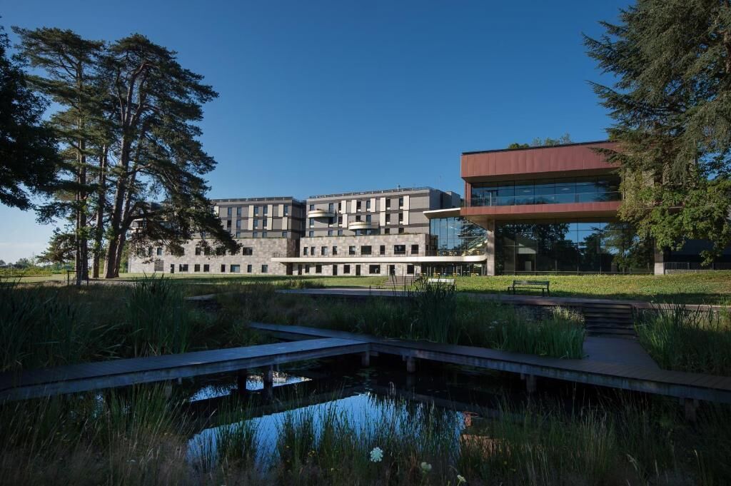 A modern building with a flat roof, large windows, and a mix of stone and metal construction.