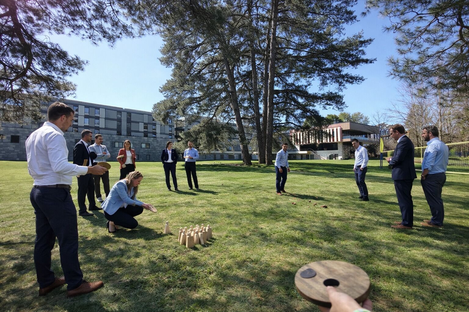 A group of people playing a game outdoors with a building in the background.