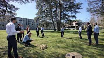 A group of people playing a game outdoors with a building in the background.