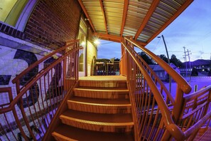 A staircase with wooden steps and metal railings leading to a covered area with a view of the surrounding area. - Lumberyard Loft in Downtown Brevard (Brevard)