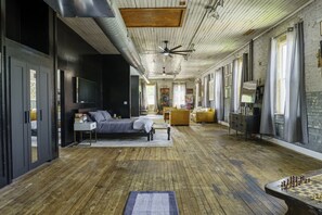 Una habitación amplia con cama, sofá, escritorio y un tablero de ajedrez.