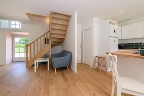 Una cocina moderna con armarios blancos, una escalera de madera y una silla azul.