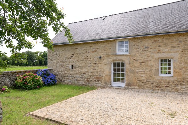 Un edificio de piedra con camino de grava, una puerta y una ventana.