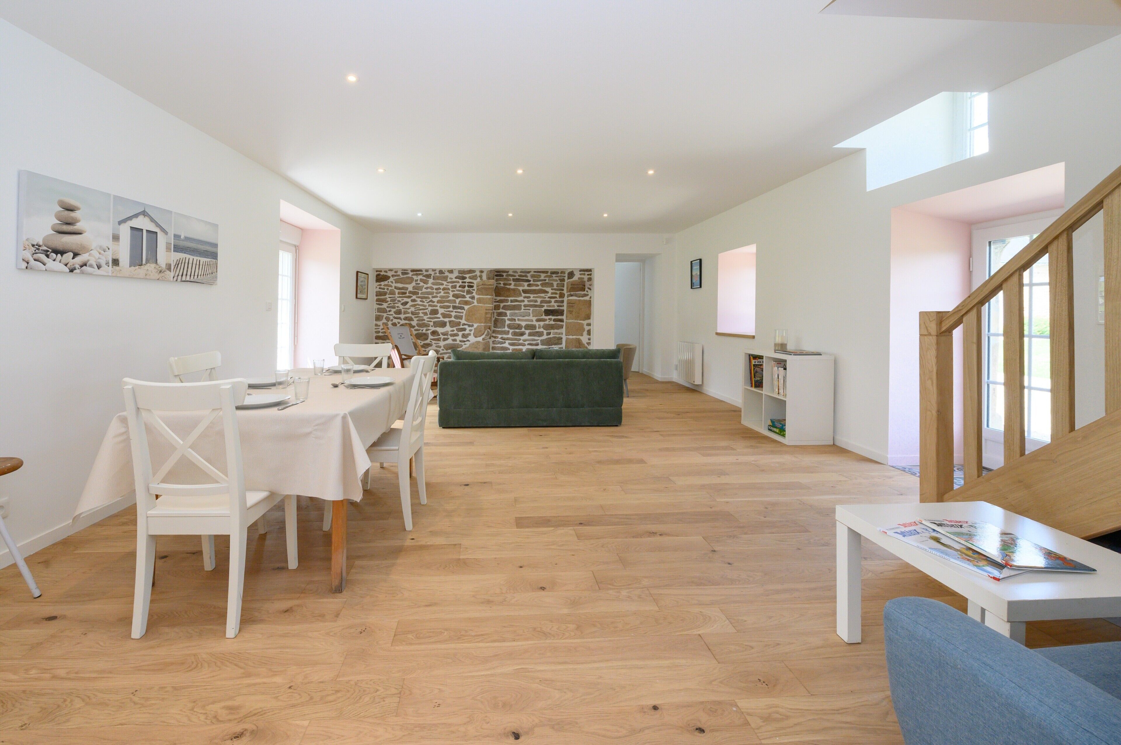 Un amplio espacio de sala con una mesa de comedor, sillas, un sofá y una escalera.