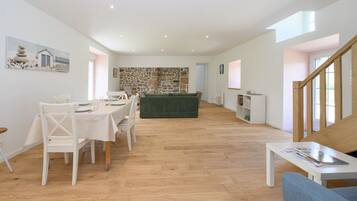 Un amplio espacio de sala con una mesa de comedor, sillas, un sofá y una escalera.