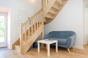 A modern interior with a wooden staircase, a blue sofa, and a small white table.