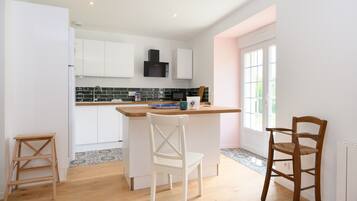 Una cocina con gabinetes blancos, una campana extractora negra, encimera de madera y salpicadero de azulejos.