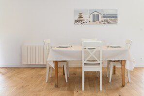 Un comedor con una mesa y sillas blancas, un radiador y un cuadro colgado en la pared.