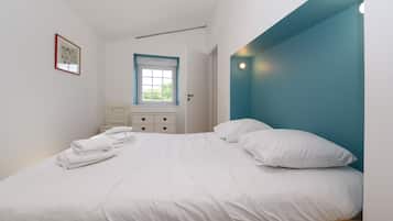Une chambre à coucher avec un lit, une fenêtre, une table de chevet et un tableau accroché au mur.