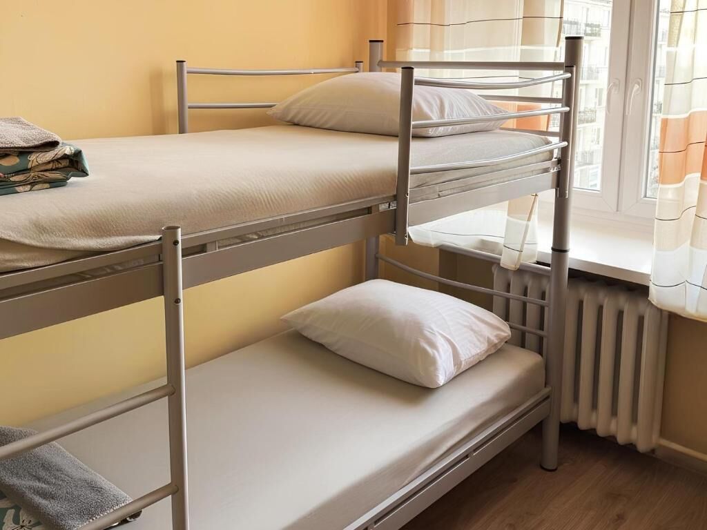 Dormitorio con literas, radiador, cortinas y ventana.