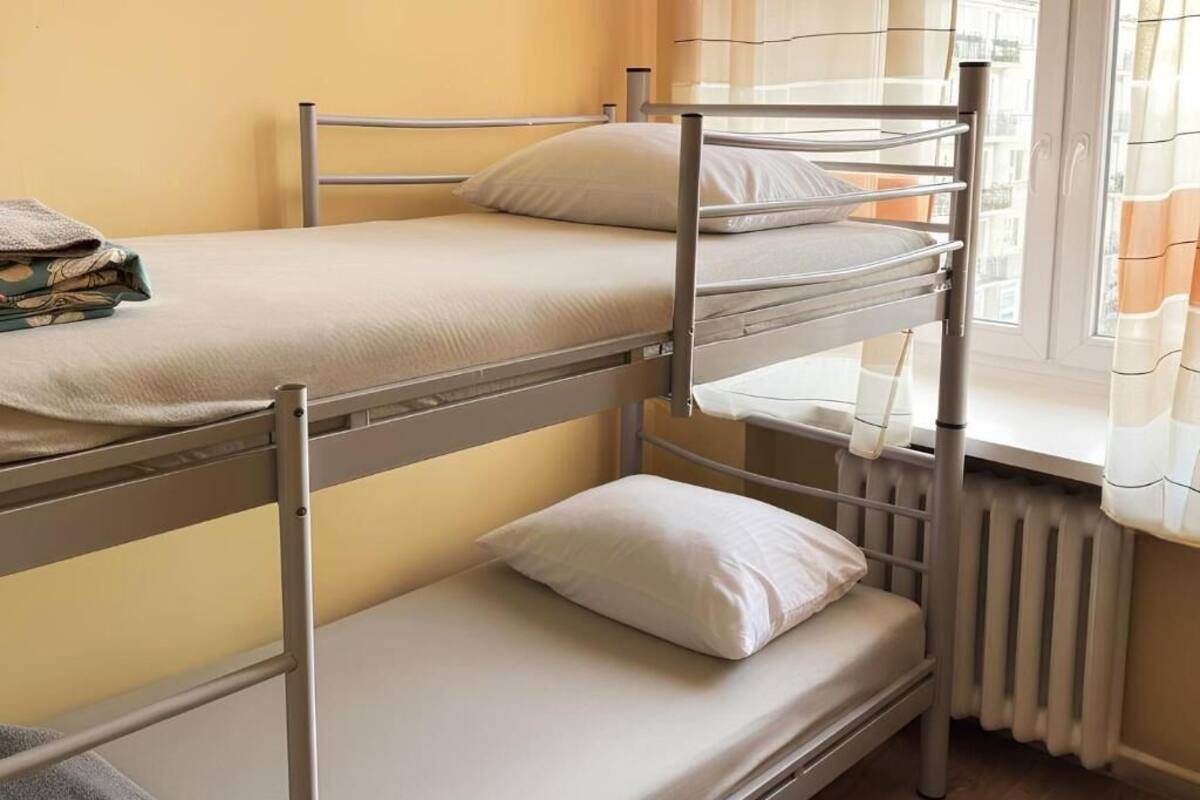A bunk bed room with a radiator, curtains, and a window.