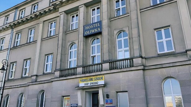 En byggnad med en skylt som visar ”Hostel Oliwka” och en annan skylt som visar ”Podreczniki Szkolne”, vilket indikerar en skolkantin.