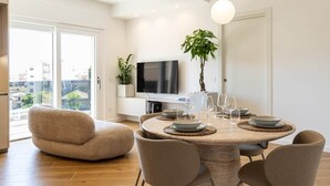 A modern dining area with a round table, chairs, and a television above. - DKV Collection 15-Elegant Apt 2BedRooms Pigneto MetroC (Rome)