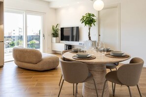 Ein moderner Essbereich mit einem runden Tisch, Stühlen und einem Fernseher darüber.