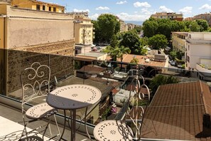 Ein Balkon mit Tisch und Stühlen, mit Blick auf eine Stadtlandschaft mit Gebäuden und Bäumen.