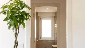 A hallway with a potted plant, a bathroom with a glass shower, and a wooden floor. - DKV Collection 15-Elegant Apt 2BedRooms Pigneto MetroC (Rome)
