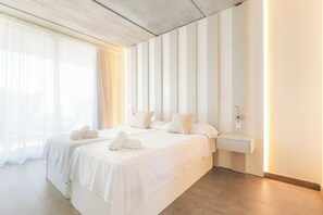 A modern hotel room with a large bed, a bedside table, and a view of the outdoors. - Villa Lumina w/ Arcade & Pool, PS5 (Can Picafort)