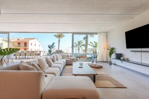 A modern living room with a sofa set, a coffee table, and a TV mounted on the wall. - Villa Lumina w/ Arcade & Pool, PS5 (Can Picafort)