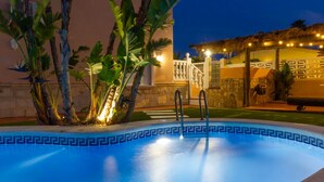 A swimming pool with a geometric tile pattern, surrounded by tropical plants and a building with a white balcony and railing. - Marena Resort Townhouse (Oliva)