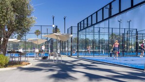 An outdoor tennis court with a net, seating area, and umbrellas. - Marena Resort Townhouse (Oliva)
