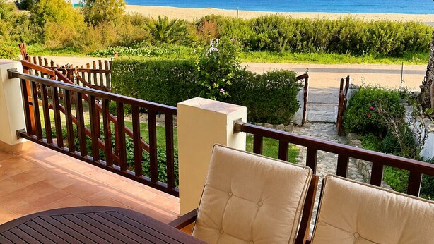 A terrace with a table, chairs, and a view of the beach and mountains. - Sealine villa with an amazing view of Tavolara (olbia)