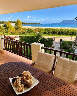 A terrace with a table, chairs, and a view of the beach and mountains.