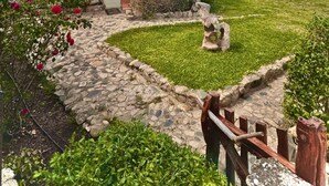 A modern building with a stone pathway leading to a grassy area, a small garden with red flowers, and a clear blue sky. - Sealine villa with an amazing view of Tavolara (olbia)