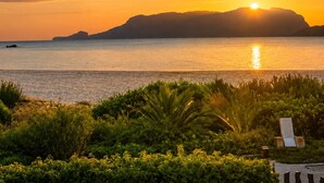 A sunset view over a calm sea with a chair and greenery in the foreground. - Sealine villa with an amazing view of Tavolara (olbia)