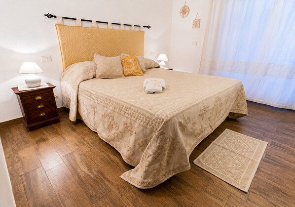 A bedroom with a bed, bedside tables, a nightstand, a rug, and a curtain.
