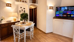 A dining area with a table set for four, a television mounted on the wall, and a plant on the table. - Sealine villa with an amazing view of Tavolara (olbia)
