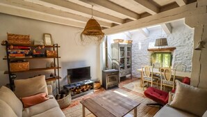A cozy living room with a fireplace, wooden beams, and a stone wall. - El Refugio de Paz - Charming cottage in Riaza (Martin Muñoz De Ayllon)