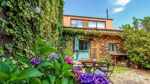 A stone building with a wooden table and chairs in the garden. - El Refugio de Paz - Charming cottage in Riaza (Martin Muñoz De Ayllon)