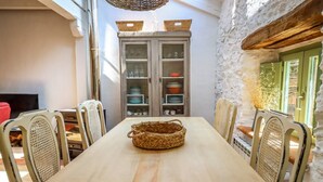 A dining area with a wooden table, wicker chairs, and a cabinet with dishes. - El Refugio de Paz - Charming cottage in Riaza (Martin Muñoz De Ayllon)
