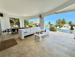 Ein modernes Wohnzimmer mit einem weißen Sofa, einem Essbereich mit Stühlen, einem Couchtisch und einem Ventilator.