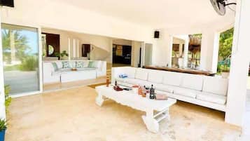 A spacious living area with a white sofa, a coffee table, and a fan.