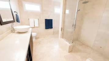 Kylpyhuone, jossa on lasiseinällä varustettu suihku, pesuallas ja wc.