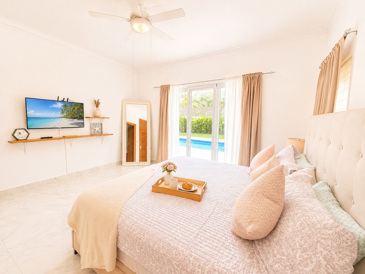 Une chambre avec un lit, une télévision, une fenêtre avec des rideaux et une vue sur une piscine.