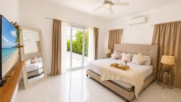 A spacious bedroom with a large bed, a ceiling fan, and a view through the glass door.