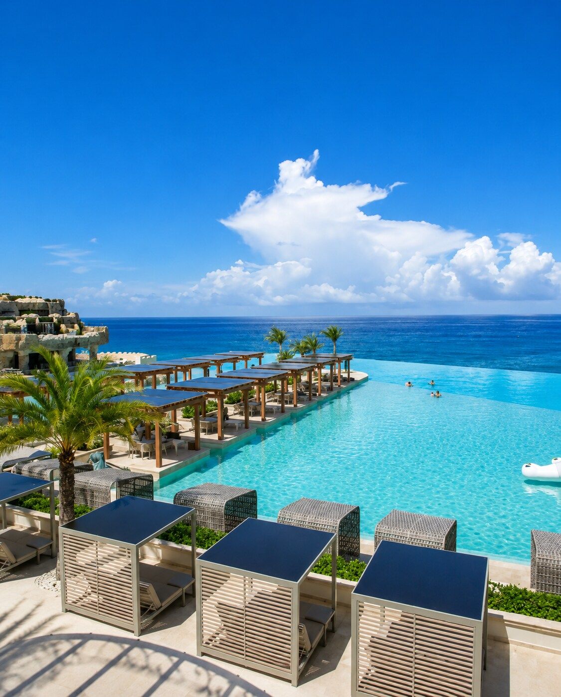 A resort pool with lounge chairs and a view of the ocean.